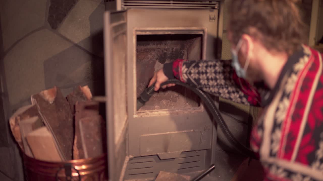 노르웨이 트론델라그 카운티 인드레 포센 에 있는 목재 스토브 내부 에서 재 를 청소 하기 위해 진공청소기 를 사용 하고 있는 사람 - 근접