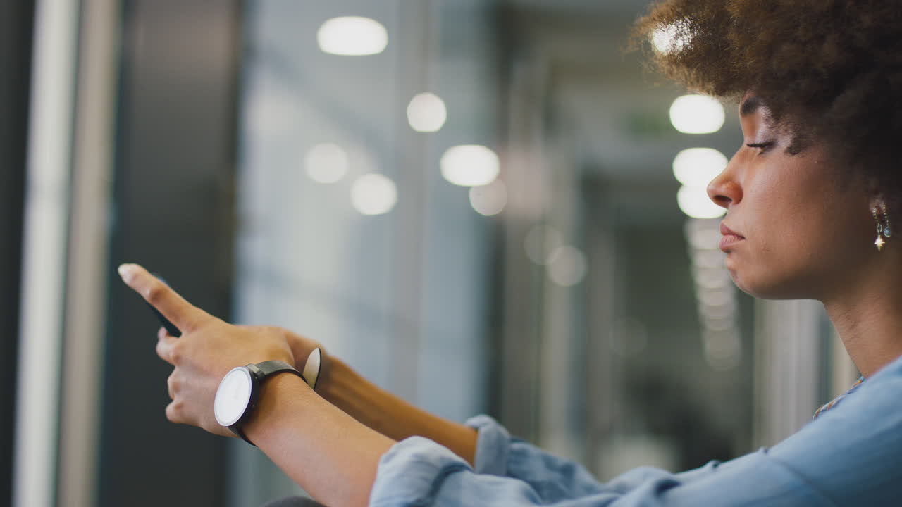 mujer de negocios joven estresada sentada en el piso en el corredor de una oficina moderna con teléfono