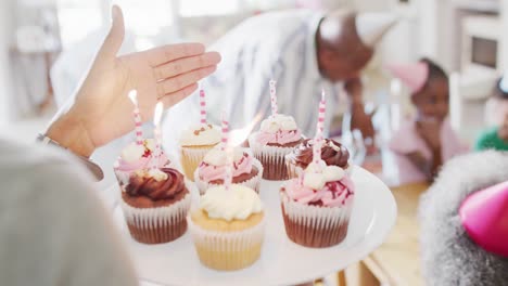 Fröhliche-Afroamerikanische-Familie-Feiert-Den-Geburtstag-Ihrer-Tochter-Mit-Kerzen-In-Cupcakes,-Zeitlupe