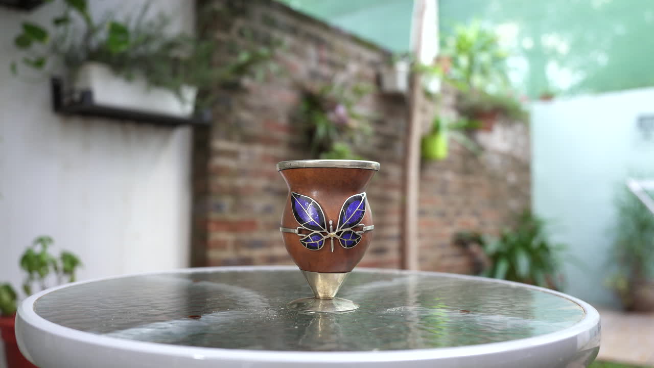 manos sacudiendo suavemente una calabaza mate, demostrando el proceso de agitar las hojas de yerba mate para mejorar la infusión de mate