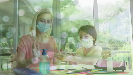 animation of light spots over caucasian woman and her daughter wearing face masks disinfecting hands