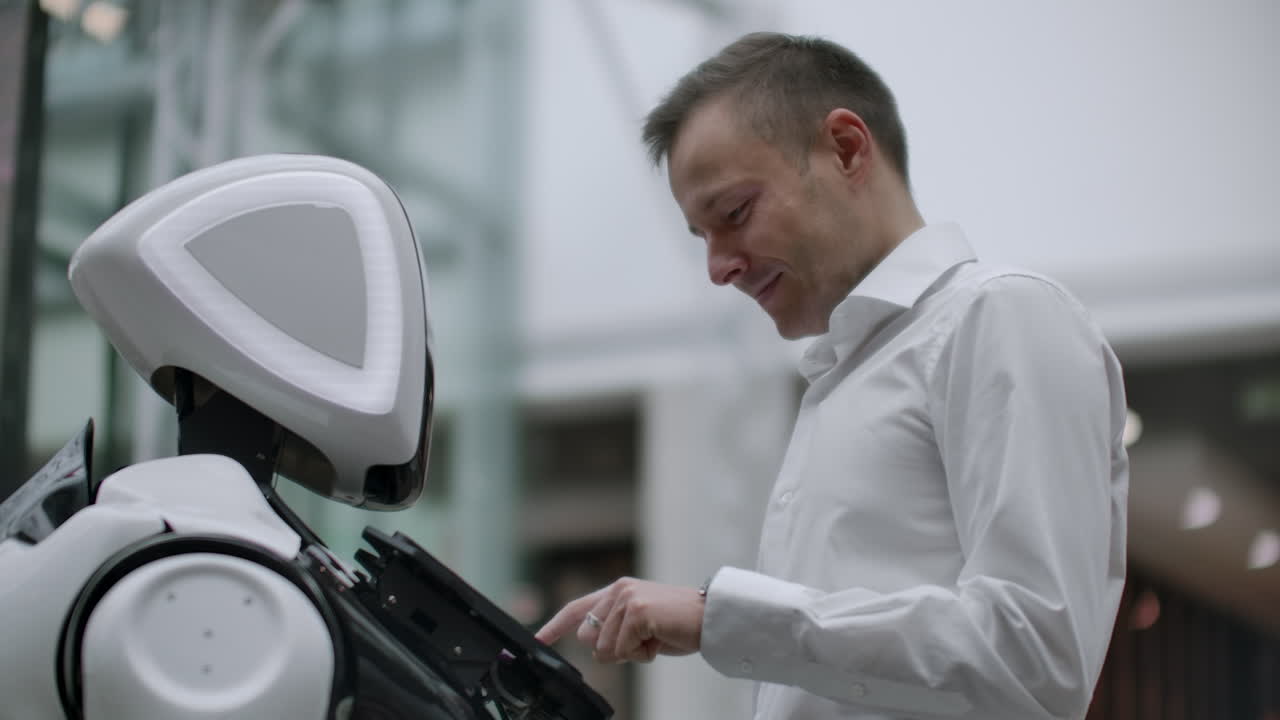 el hombre en el centro comercial se comunica con un asesor robot. tienda moderna y vendedor robot. robot ayuda a un hombre en el centro comercial.