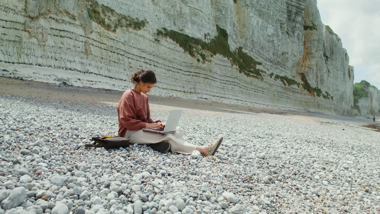 Woman Working on Laptop on a Beach