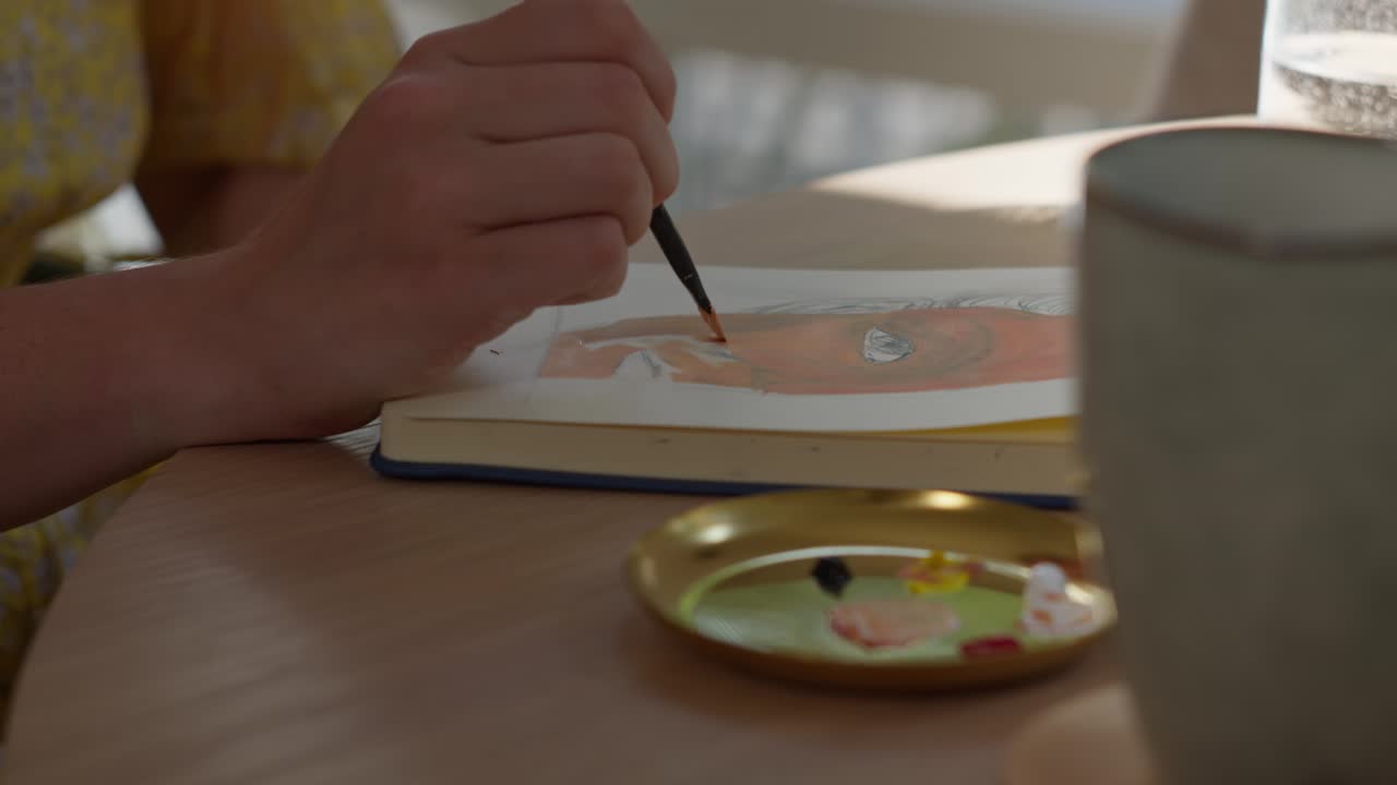 여자 는 아파트 에서 그림 을 그리는 동안 페인트 에 브러쉬 를 묻는다