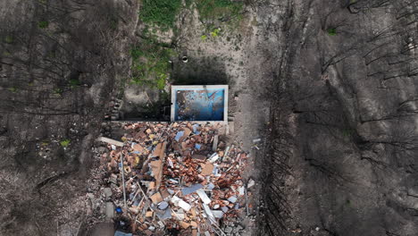 rising aerial view above remains of pool and demolished house after forest wildfire