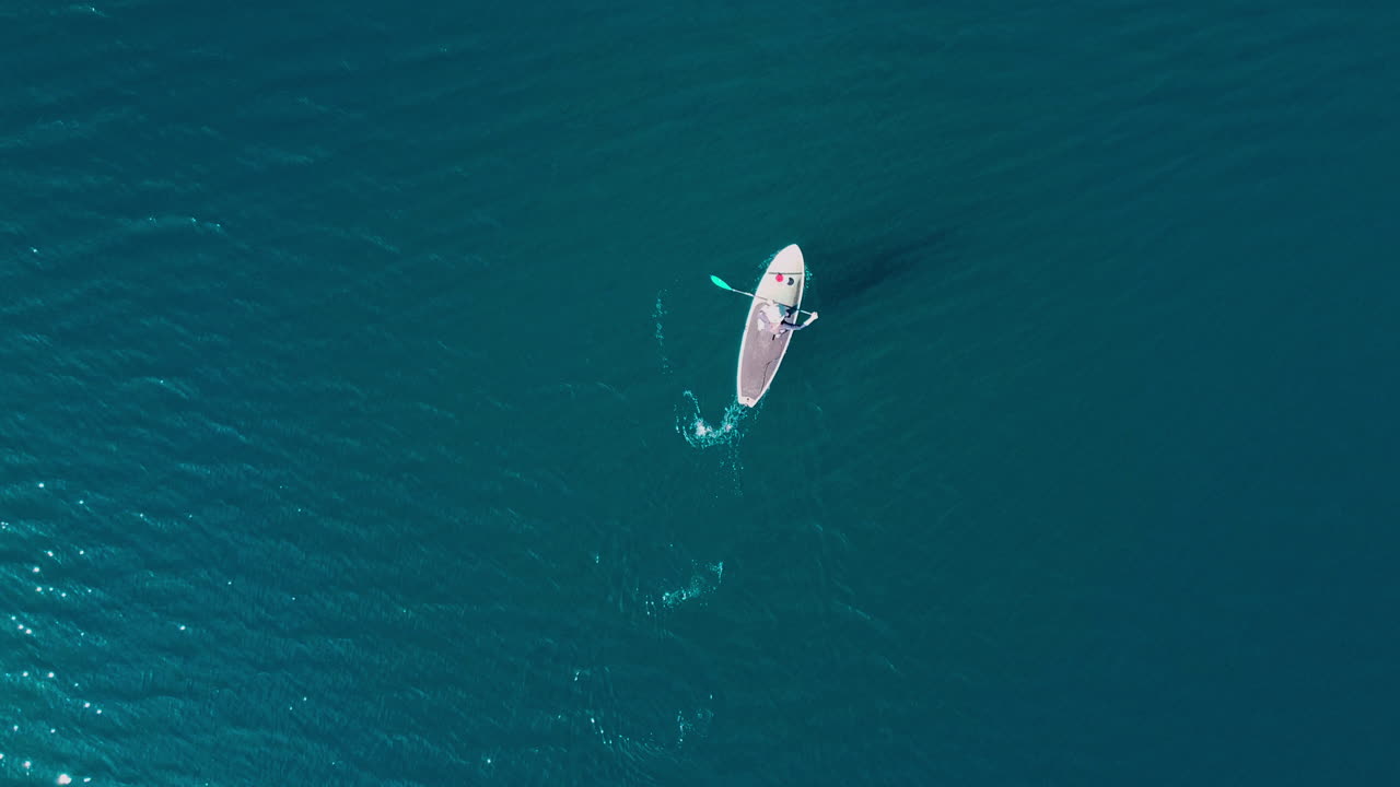 Bird's eye view drone shot of a paddle boarder on a lake at Kai Iwi Lake, New Zealand