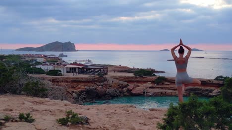 dramatic aerial top view flight yoga girl position tree sunset cliff beach island ibiza spain very close passing flight drone