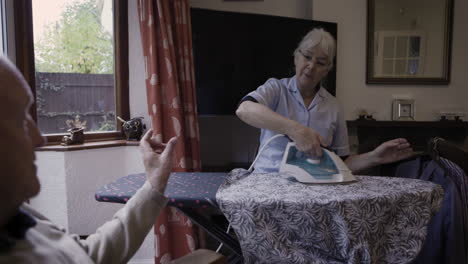 nurse ironing clothes for senior citizen at home