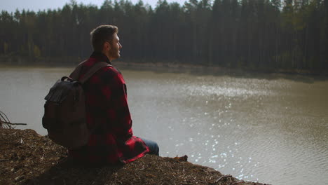 on a walk. hiker walking in a forest. tourist guy in black hoodie wearing and standing on pier of cinematic lake on cold spring morning. inspiration shot. high quality 4k footage