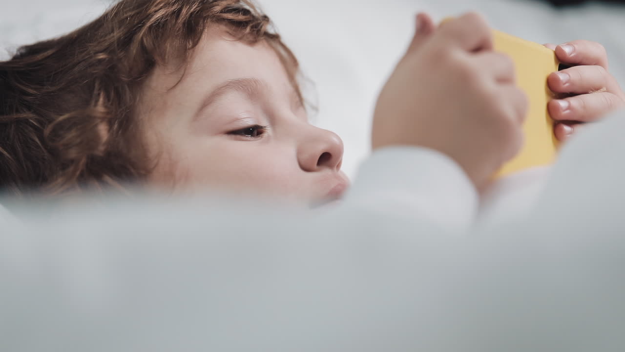 Child using phone in bed