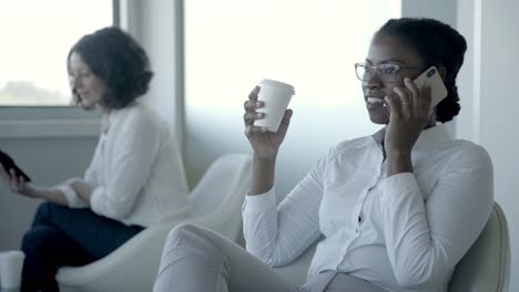 Smiling-young-businesswoman-talking-by-smartphone