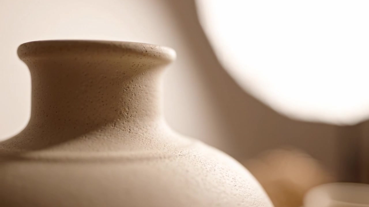 Vista ravvicinata di un vaso di ceramica liscio e non rifinito che evidenzia la sua forma elegante e la sua texture sotto illuminazione naturale in un ambiente da studio