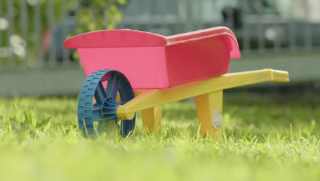 Close-up-shot-of-a-kids-wheelbarrow-standing-in-a-garden