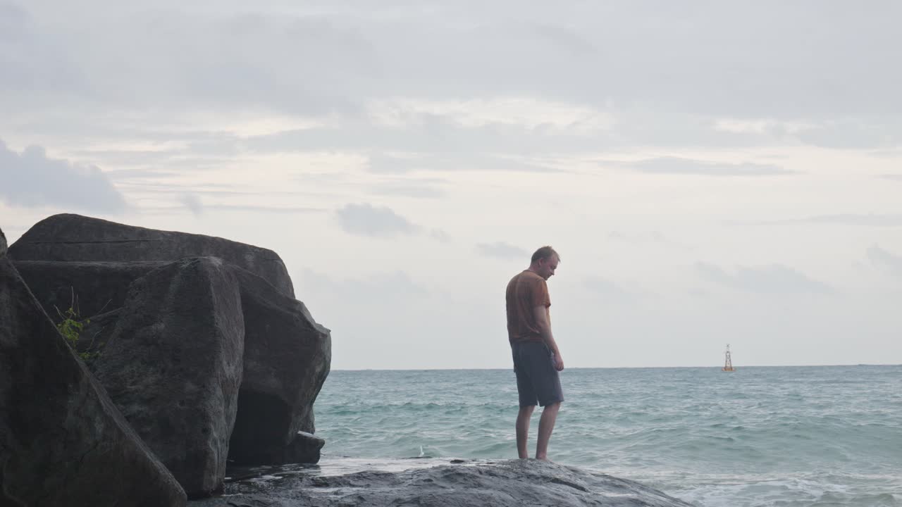hombre de pie en la roca con olas estrelladas en la playa de dam trau en vietnam