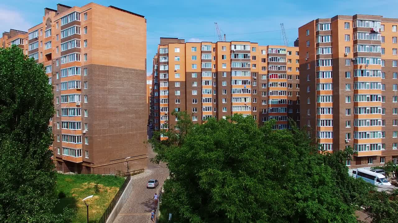 New high buildings in the city. Residential apartments under the blue sky. Architecture in brown colors in the modern district. Camera rising up.