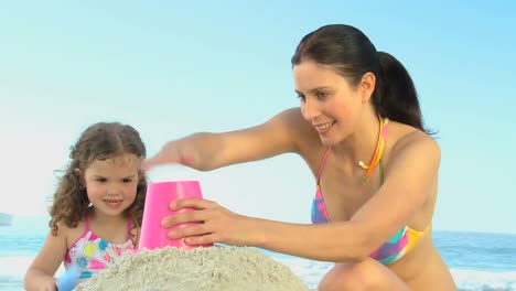 Cute-daughter-building-a-sand-castle-with-her-mother