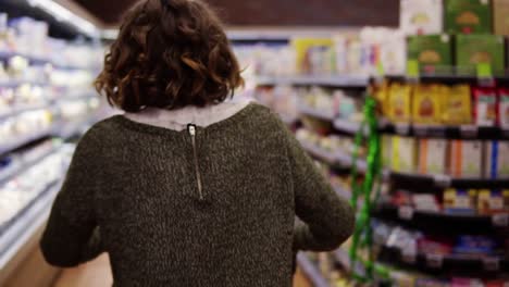 vista rara de una mujer feliz y emocionada en suéter fue de compras con un carrito de tranvía - caminar por una fila y saltar felizmente. cámara lenta