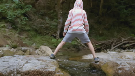 child jumping over a creek