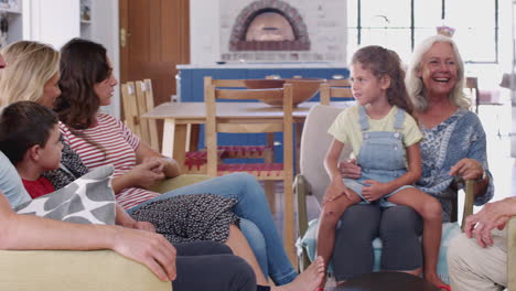 multi-generation family sitting on sofas at home talking together