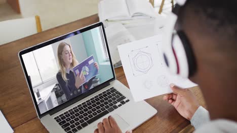 African-american-male-college-student-holding-notes-while-having-a-video-call-on-laptop-at-home