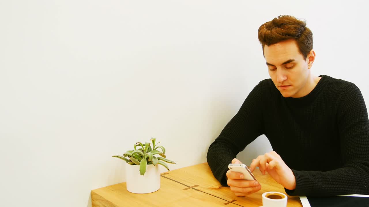 Man using mobile phone while having cup of coffee