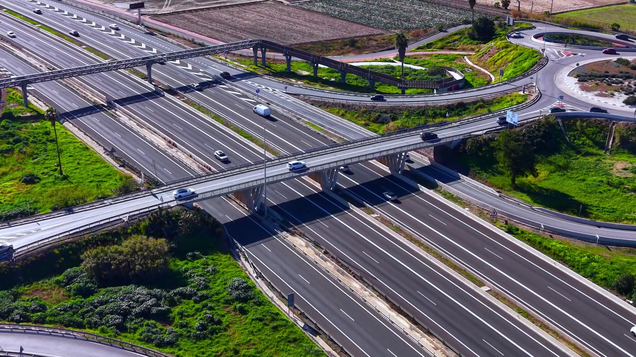Toma de gran angular de múltiples niveles de carreteras y puentes que forman un intercambio vial en una zona rural. Vista aérea oblicua de un complejo sistema de intercambio de autopistas.