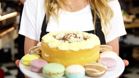 portrait of waitress holding dessert on cake stand