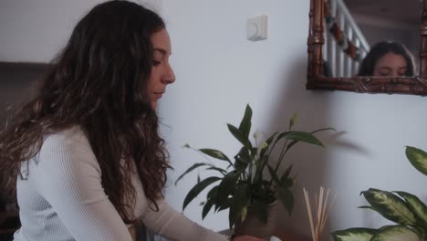 woman adjusting modern home thermostat, lowering the temperature to save on energy bills during the cost of living crisis