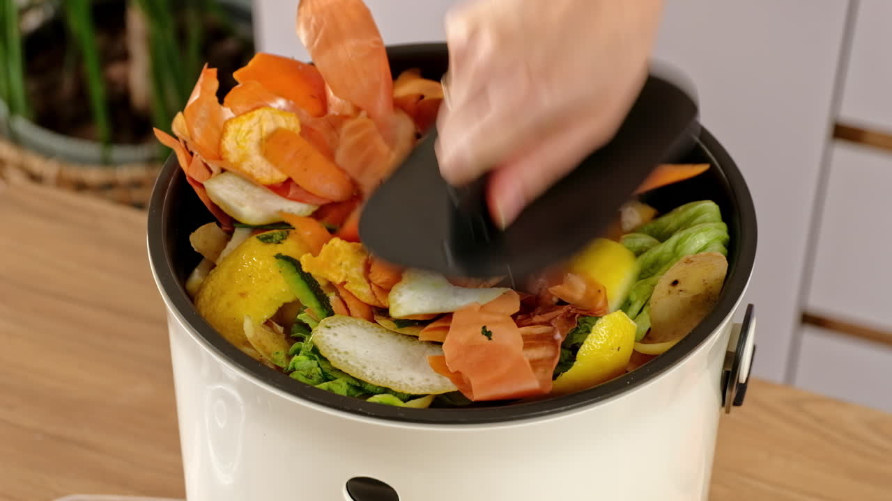 Woman recycling organic waste by composting vegetables peels in the Bokashi in the kitchen