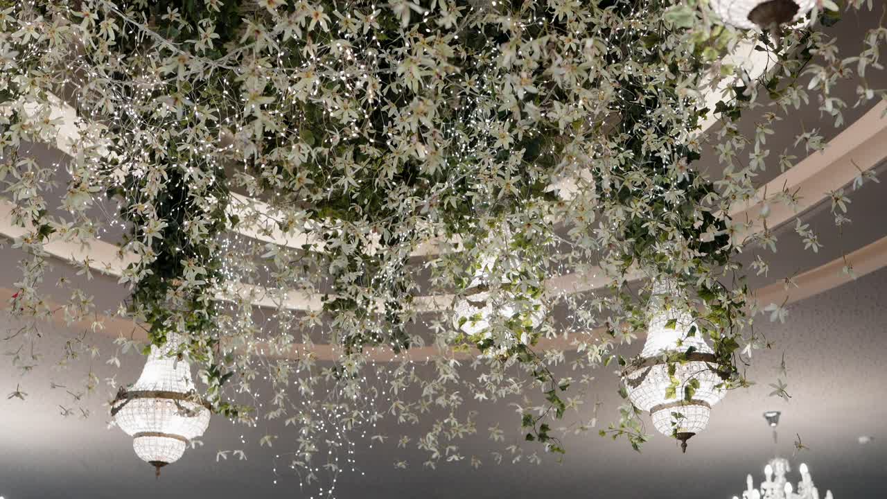 elegant floral ceiling with crystal chandeliers and cascading greenery and hanging lights