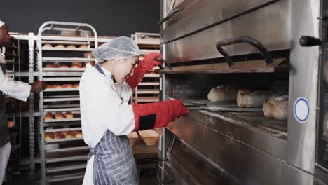 Panadera-Asiática-Trabajando-En-La-Cocina-De-La-Panadería,-Sacando-Pan-Del-Horno,-Cámara-Lenta