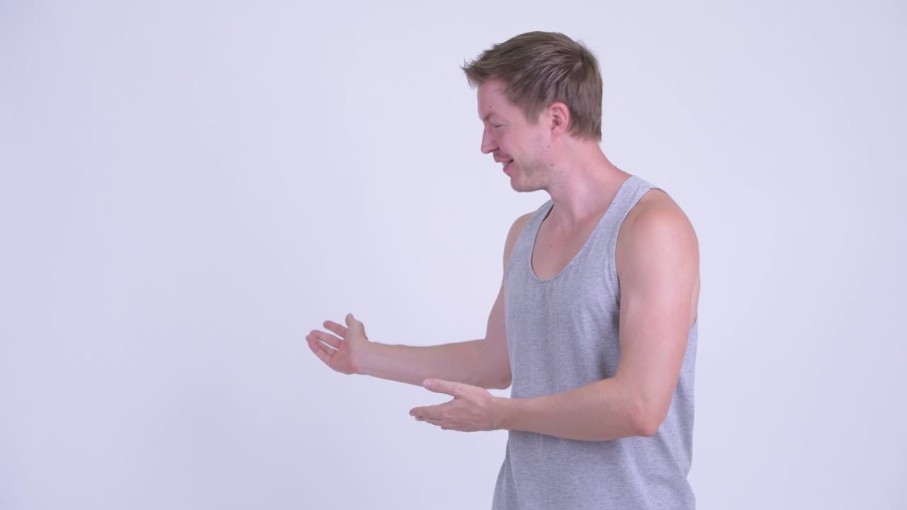 행복한 젊은 잘생긴 남자가 뒤에서 무언가를 보여줍니다.