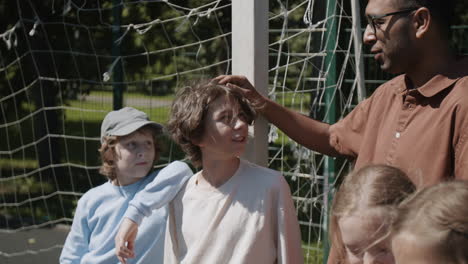 coach interacting with a group of young children on a sports field