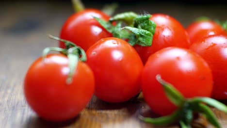 tomates cherry mojados jugosos rojos diminutos frescos crudos en la superficie de la cocina de madera enfoque selectivo dolly right closeup