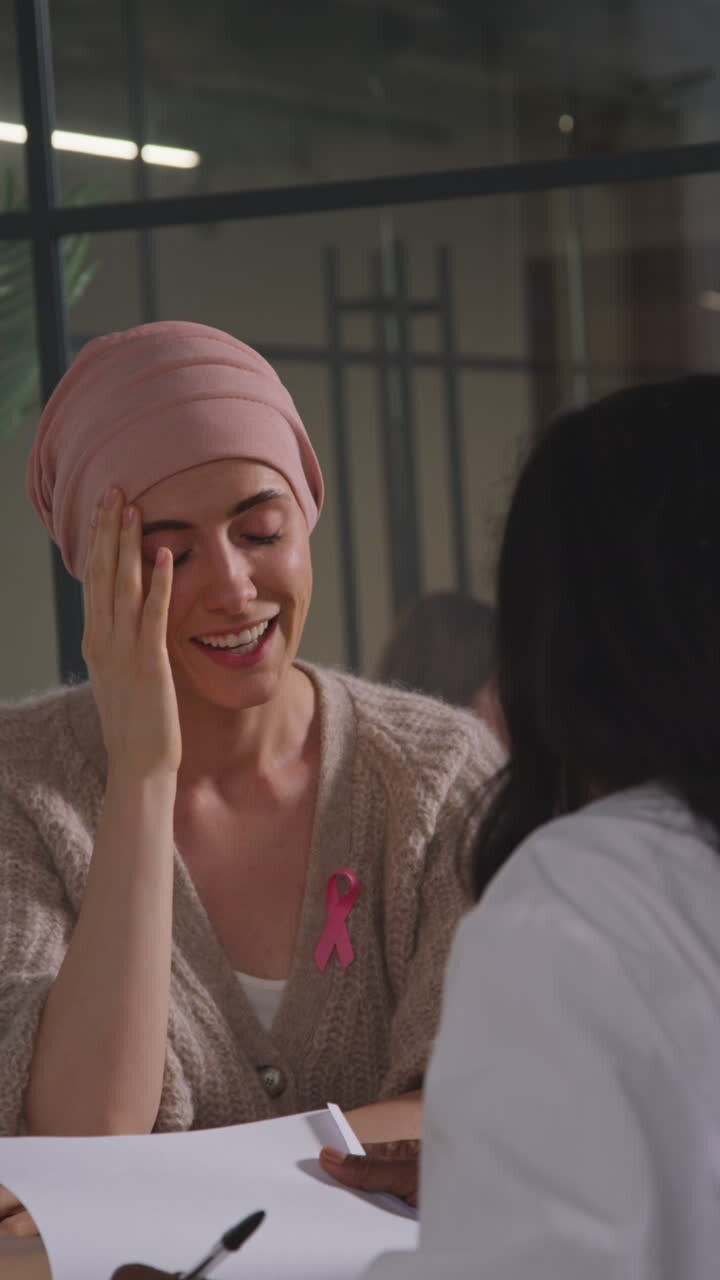 Vertical Video Of Young Woman Patient Wearing Headscarf Getting Good News At Meeting With Oncologist Or Doctor In Hospital For Breast Cancer Treatment 2