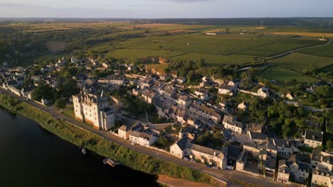 Una-Vista-Aérea-Del-Pueblo-Francés-De-Montsoreau,-En-El-Loira,-Con-Su-Histórico-Castillo-Y-Viñedos,-Bajo-El-Dorado-Sol-De-La-Mañana.