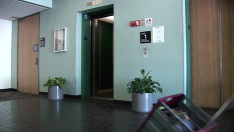 a businesswoman walks out of an elevator pulling a crate of paperwork behind her