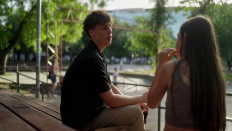 young couple talking and laughing while sitting in a skate park