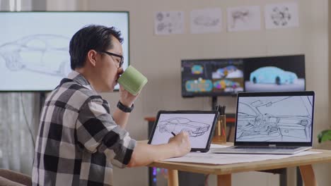 side view of asian male drinking coffee while drawing new car design concept on a tablet in the studio with tv and computers display 3d electric car model