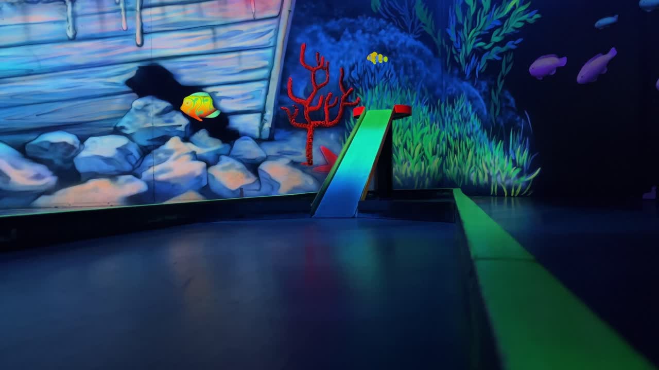 Minigolf ball hits a yellow ramp and doesn't roll up into the hole but leaves the fairway