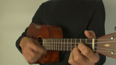 hombre tocando un ukelele con la mano