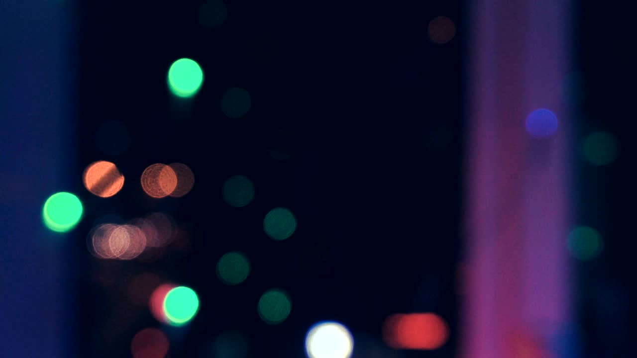 guirnalda de navidad con luces de colores junto a la ventana contra el fondo de la ciudad y el movimiento de los coches, primer plano. luces de navidad borrosas. bokeh.