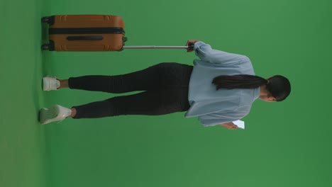 full body of back view asian woman traveler with luggage using smartphone while walking and standing in the green screen background studio, during sunset time