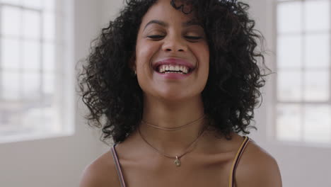 Atractivo-Retrato-De-Mujer-De-Raza-Mixta-De-Una-Hermosa-Niña-Hispana-Riendo-Feliz-Mirando-La-Cámara-Alegre-Peinado-Afro-En-El-Fondo-De-Las-Ventanas-Del-Apartamento