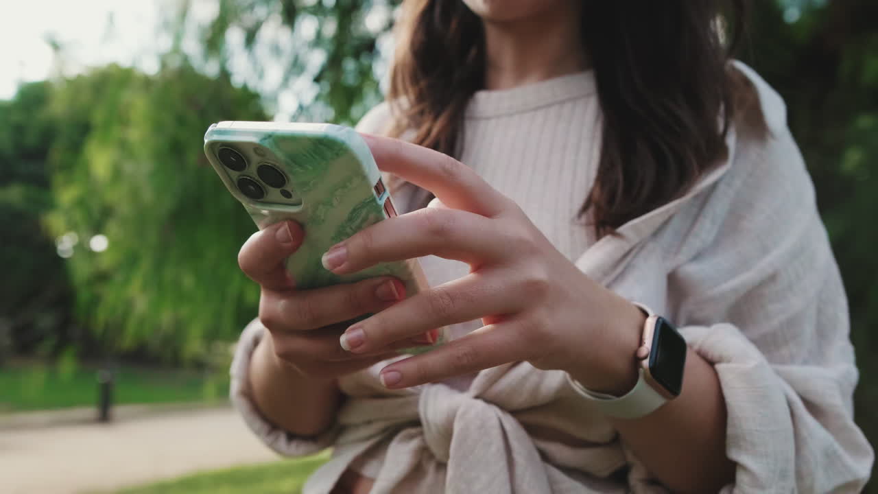 Mulher usando celular e smartwatch ao ar livre