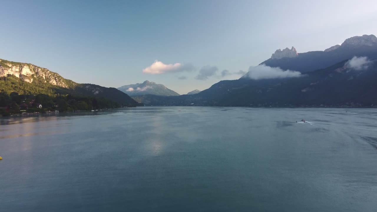 Aerial footage moving along Lake Annecy just after morning Sunrise. Footage is medium height and movi g forward with mountains in background. France, beautiful views