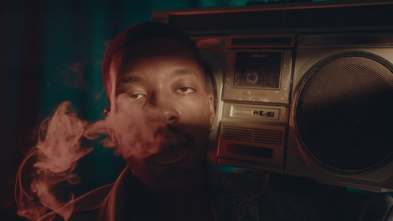 Uomo di colore con un lettore di cassette retrò che fuma guardando la fotocamera