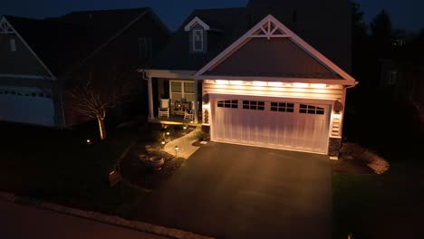 lighting garage of one family house in american neighborhood at night. aerial approaching shot of house in american city.