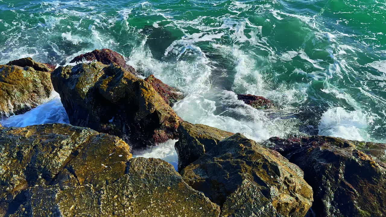 Onde si infrangono contro le rocce in una giornata di sole lungo la costa vicino a una spiaggia nel pomeriggio