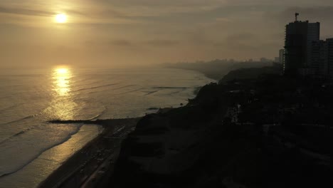 Toma-Aérea-De-La-Hermosa-Puesta-De-Sol-Tomada-En-Costa-Verde,-Costa-Peruana-Ubicada-En-La-Ciudad-De-Lima